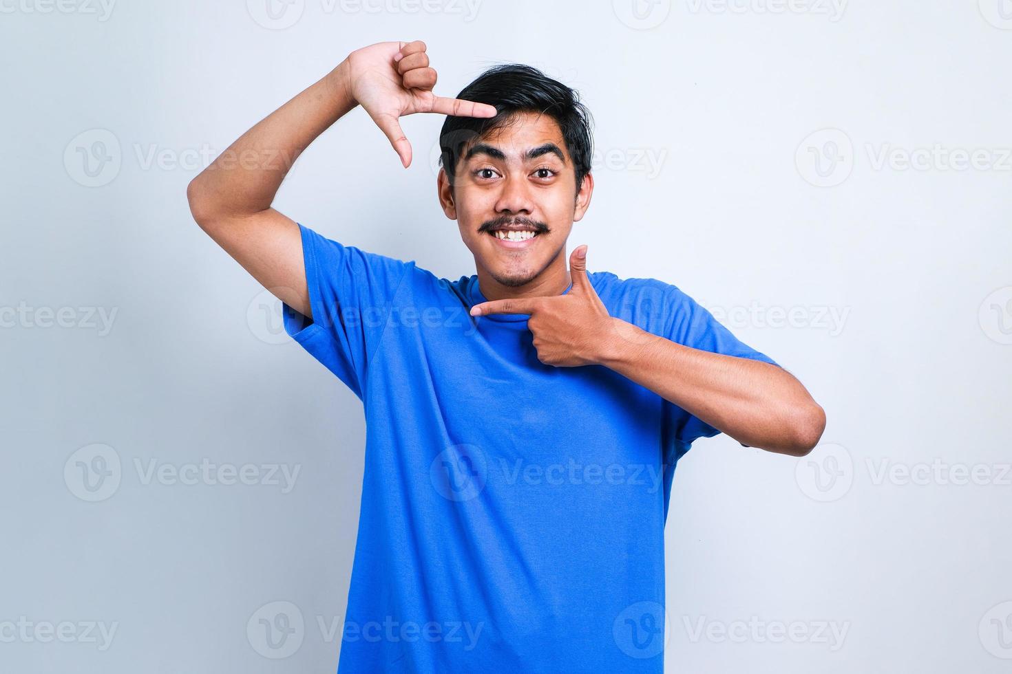 ragazzo asiatico sorridente facendo cornice con le mani e le dita con la faccia felice. concetto di creatività e fotografia foto