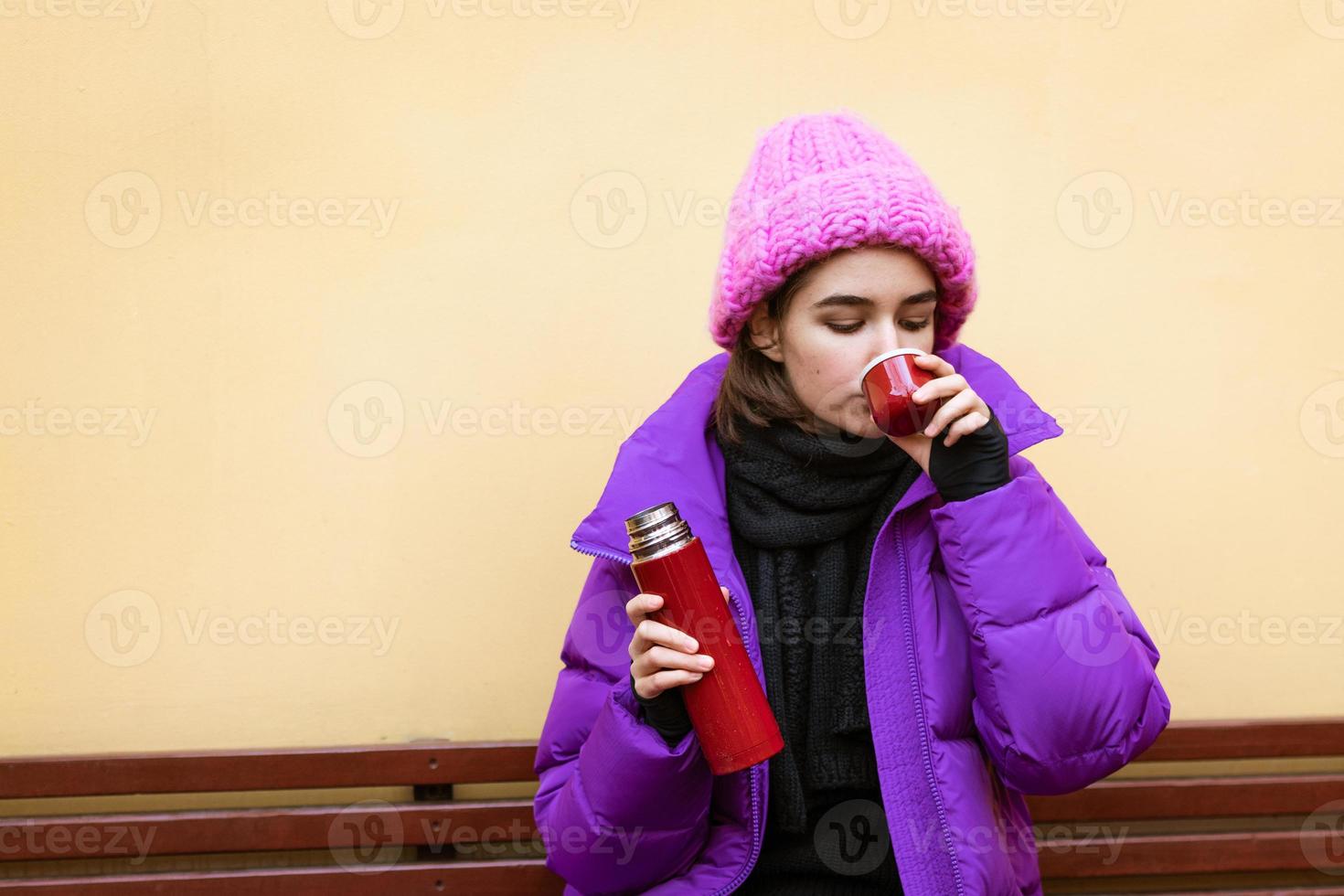 bella giovane donna caucasica che indossa abiti da neve e tiene un thermos foto