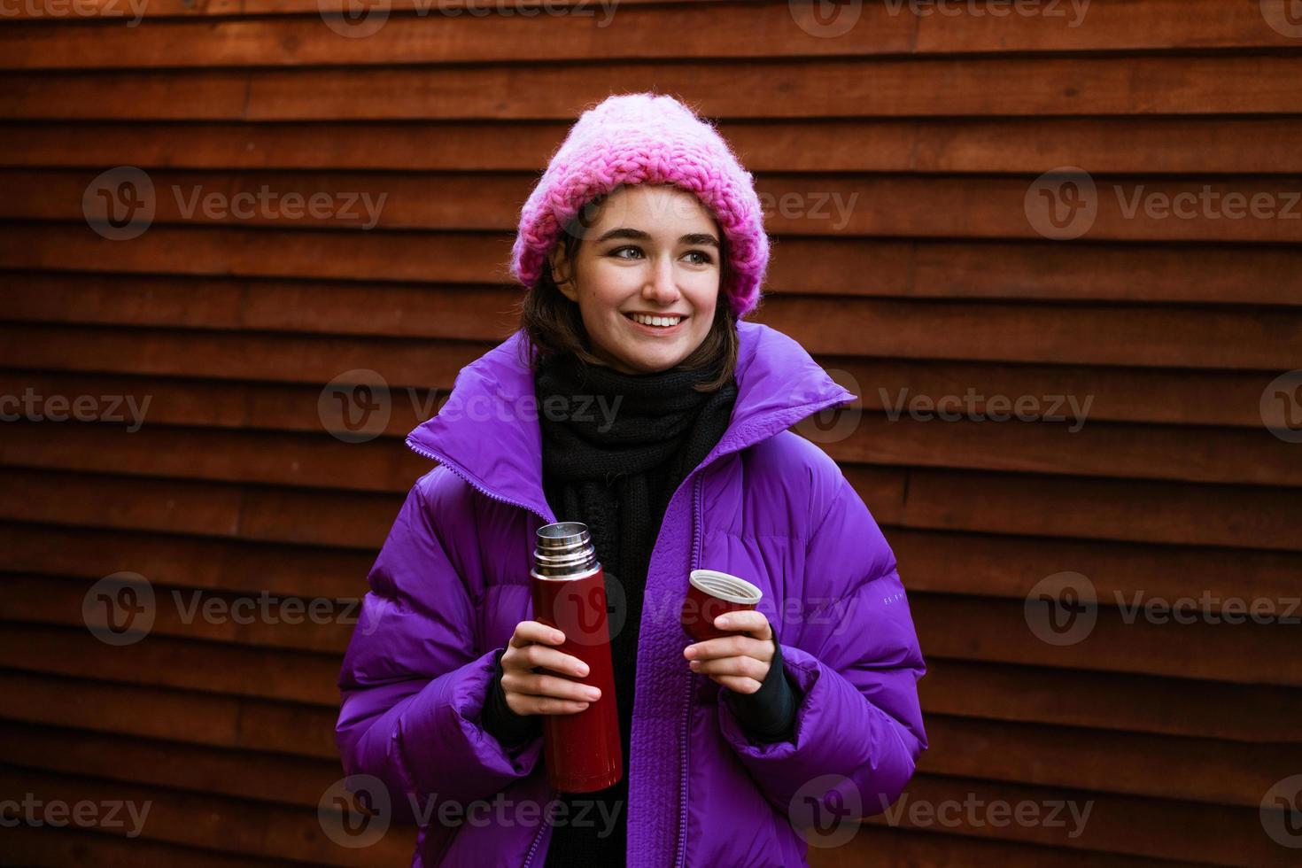 bella giovane donna caucasica che indossa abiti da neve e tiene un thermos foto