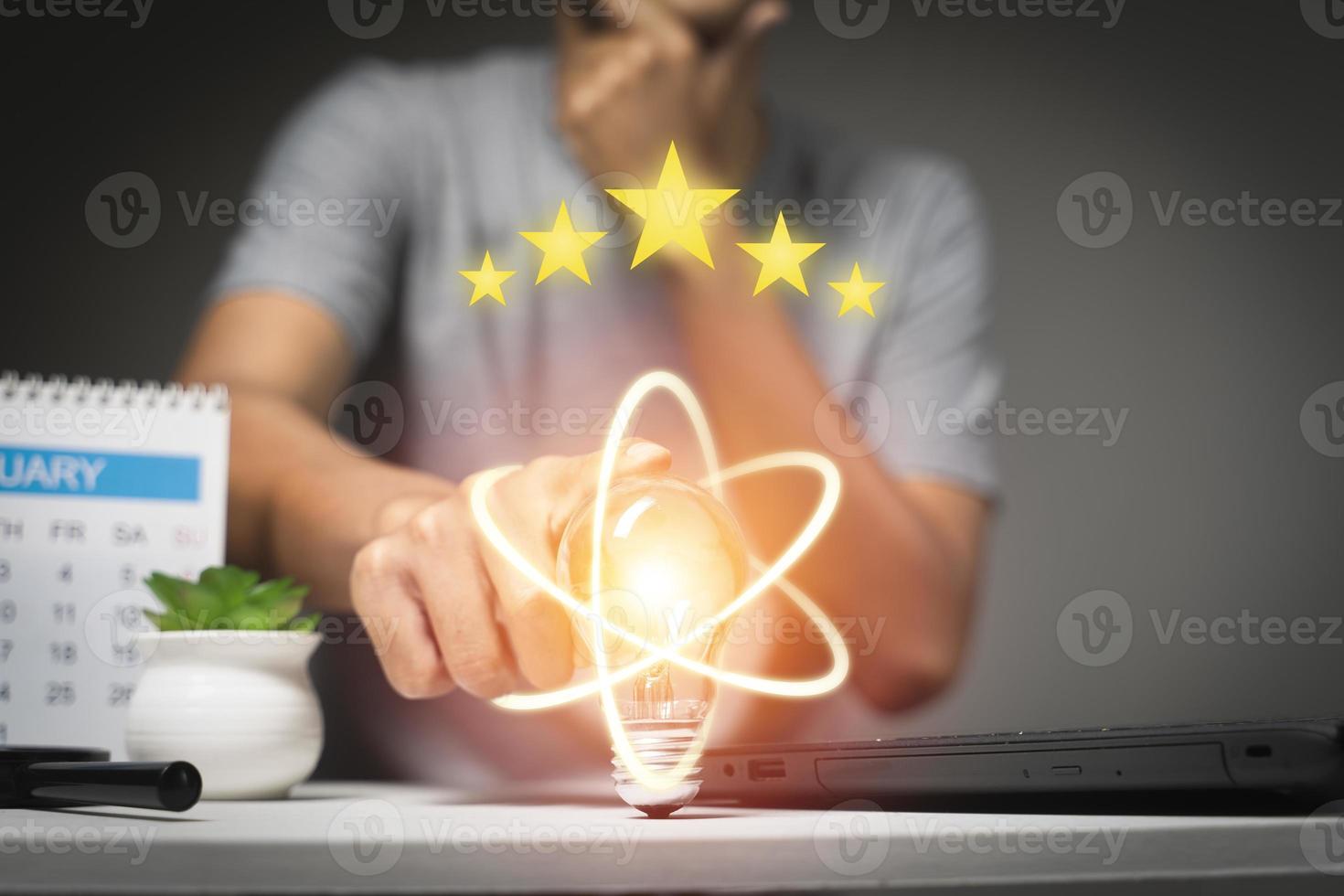 mano che tiene la lampadina cinque stelle di valutazione d'oro e idea di risparmio energetico e tecnologia aziendale concep foto