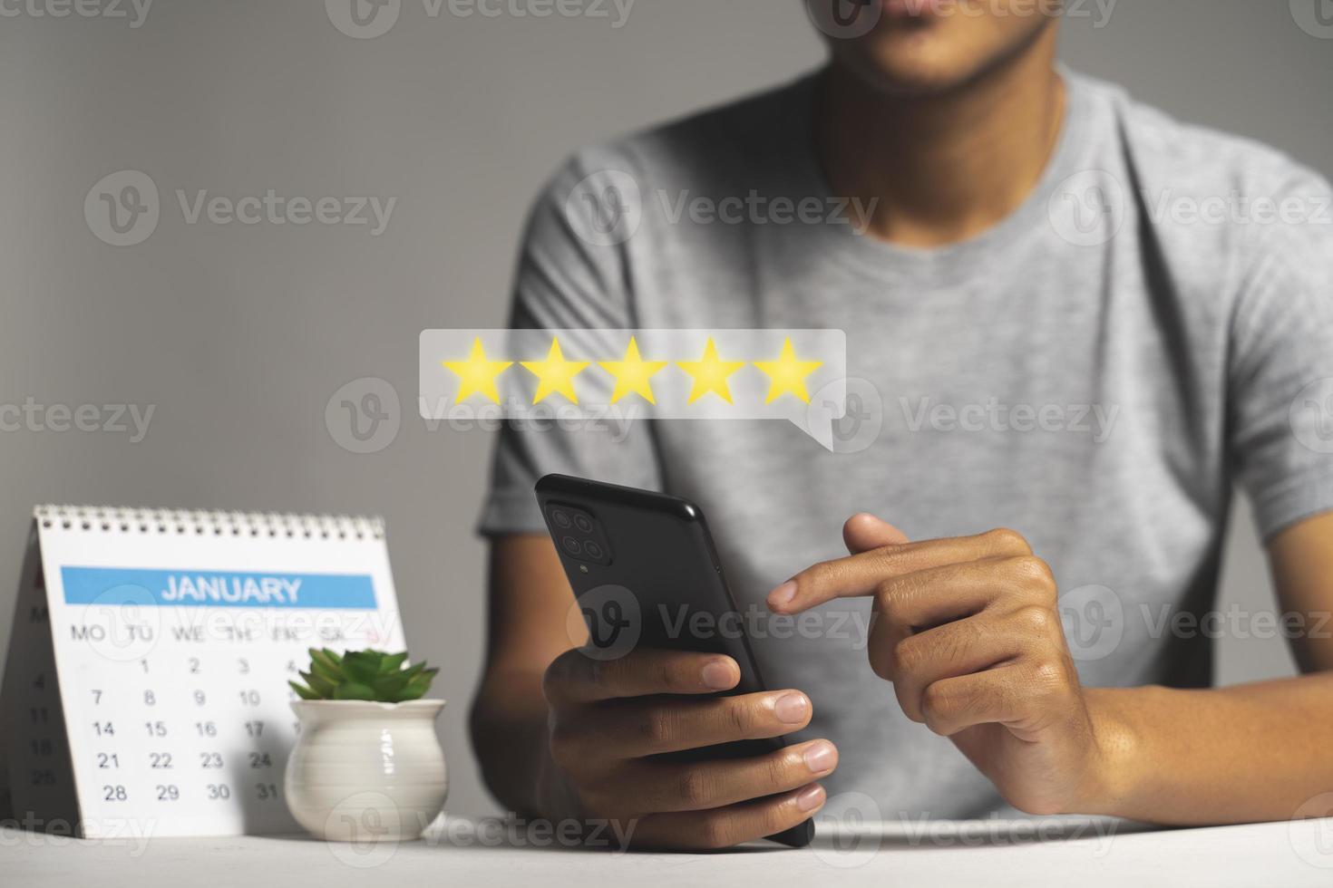 mano dell'uomo che utilizza lo smartphone con l'icona a cinque stelle popup per il servizio di soddisfazione della revisione del feedback foto