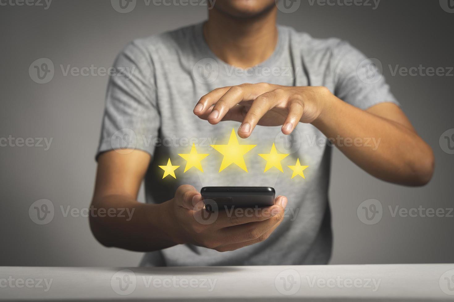mano dell'uomo che utilizza lo smartphone con l'icona a cinque stelle popup per il servizio di soddisfazione della revisione del feedback foto