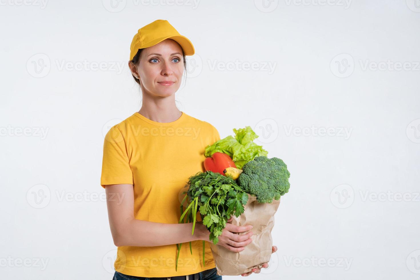 una donna in abiti gialli, consegnando un pacco di cibo, su sfondo bianco foto