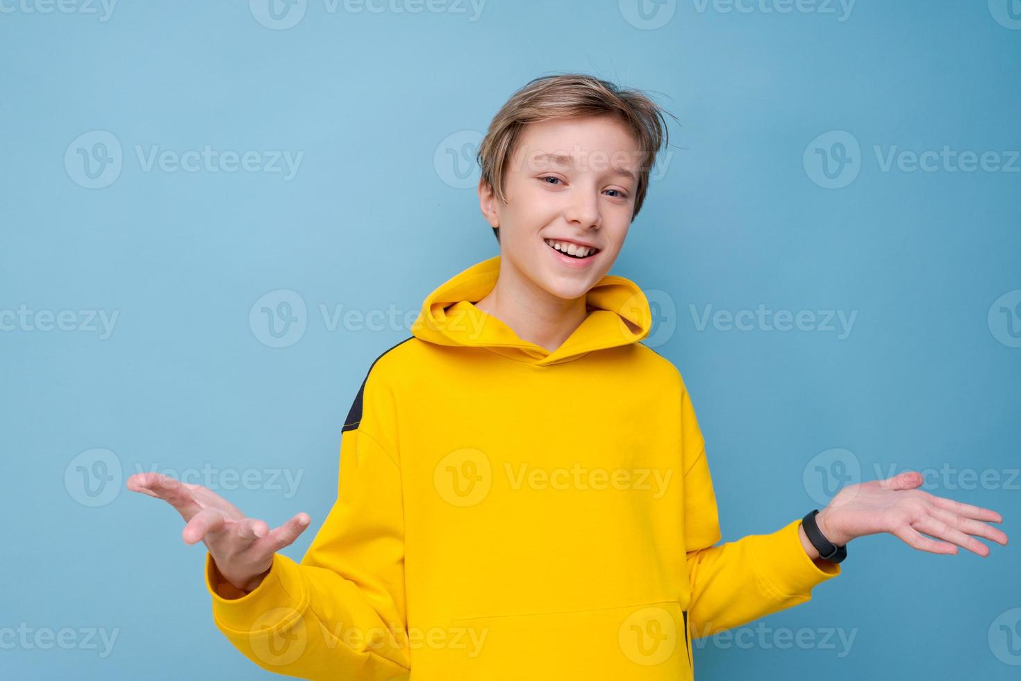 giovane sorridente felice uomo allegro in felpa gialla brillante che punta foto