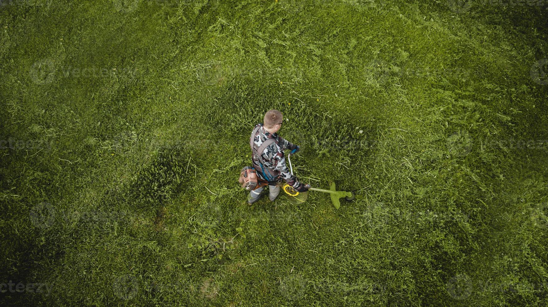 l'uomo del tosaerba falcia il prato la vista dall'alto foto