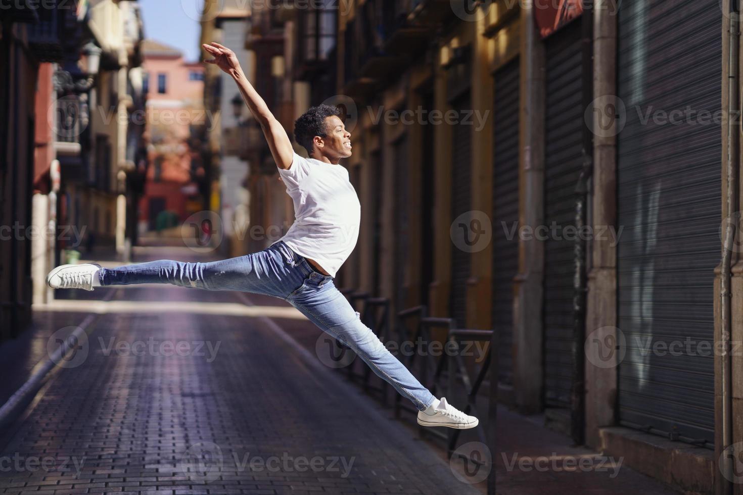 ragazzo nero felice che fa un salto acrobatico in mezzo alla strada. foto