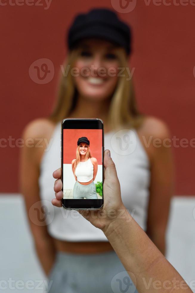 mano della donna che cattura la fotografia con uno smartphone alla sua amica foto