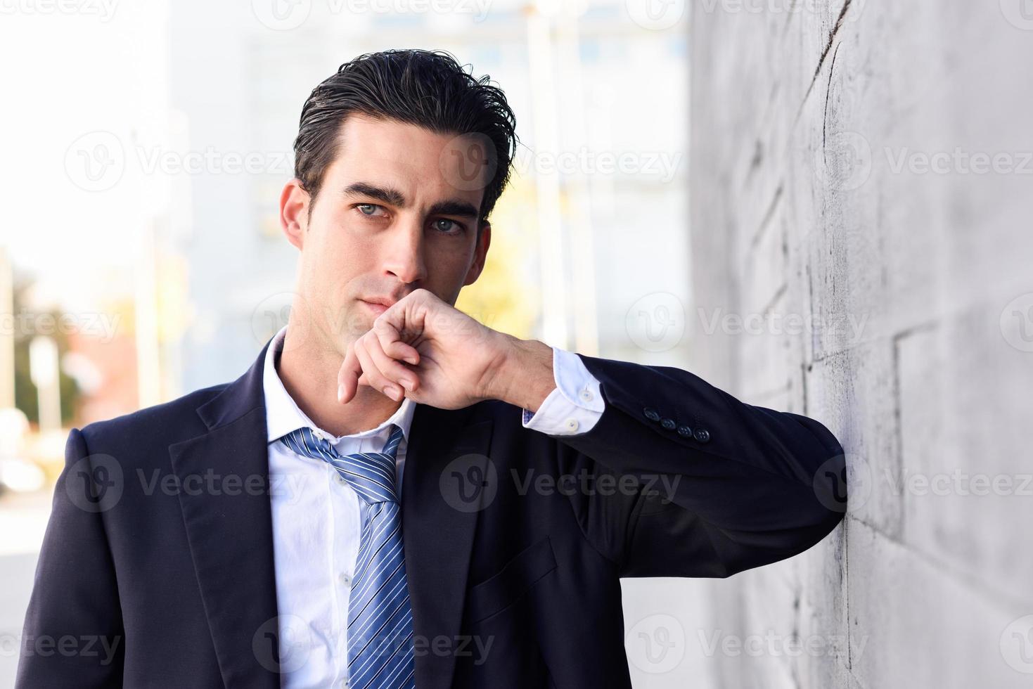 giovane uomo d'affari che indossa abito blu e cravatta in background urbano foto