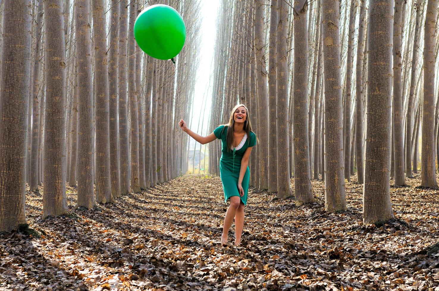 bella ragazza bionda, vestita di verde, che ride nella foresta foto