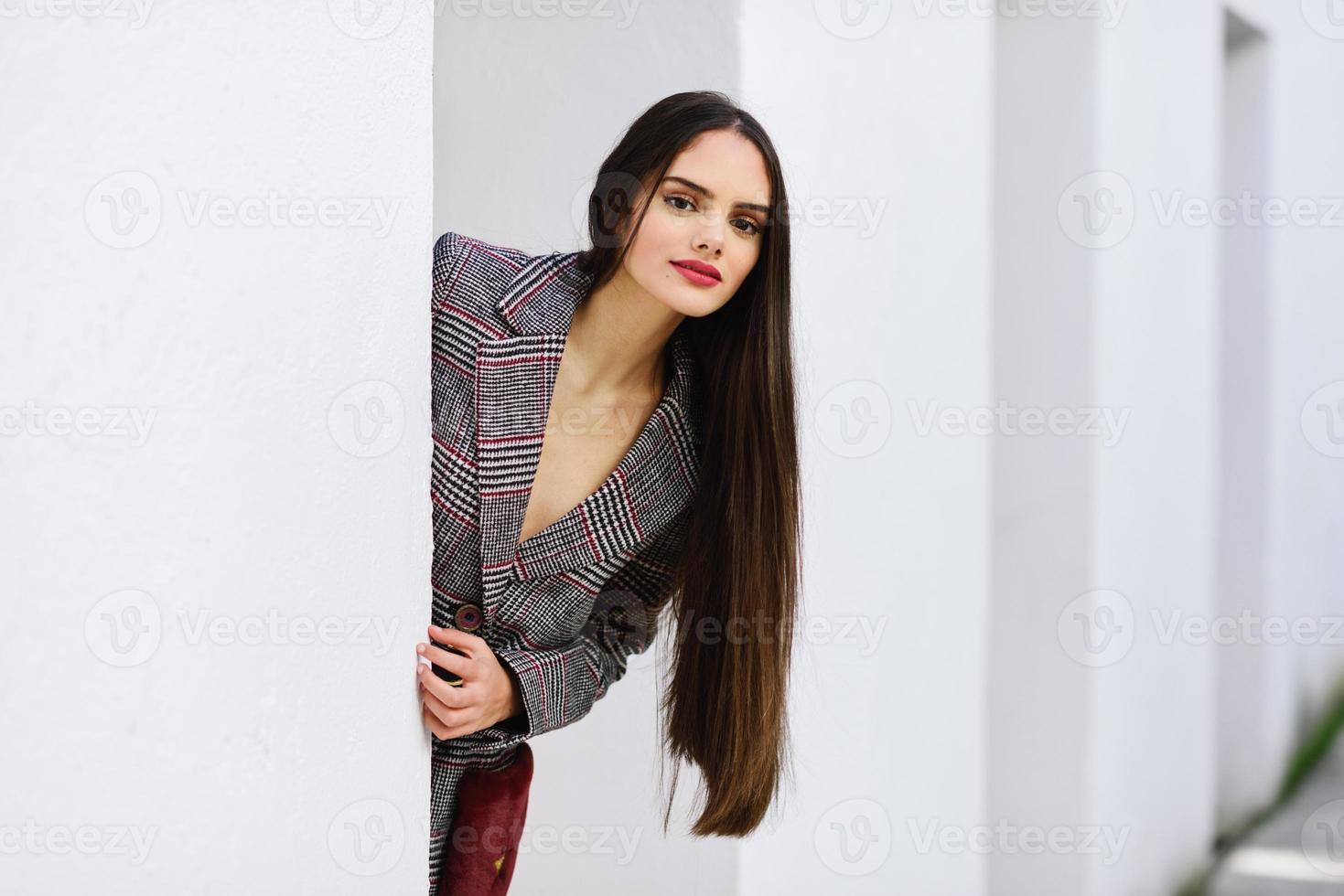 bella ragazza con capelli molto lunghi che indossa cappotto invernale e berretto all'aperto. foto