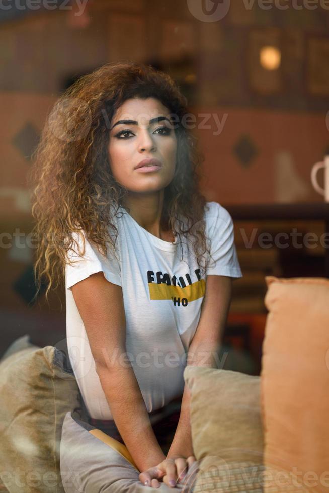 ragazza araba seduta in un bar con la faccia preoccupata foto