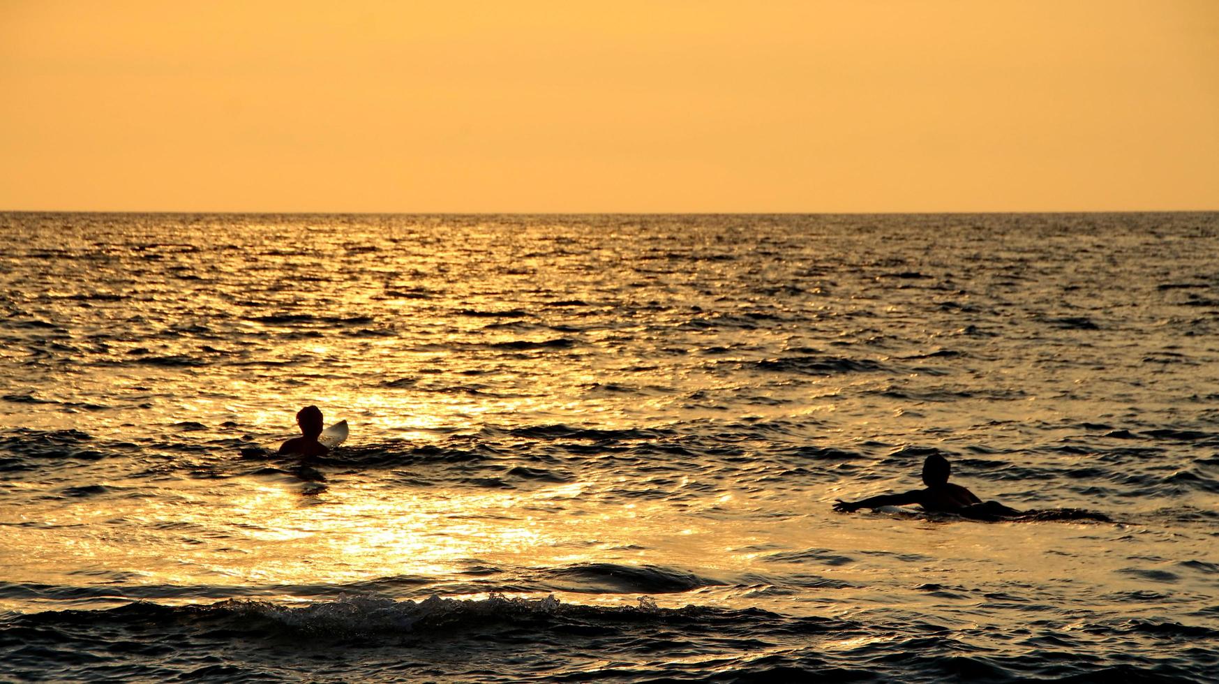 documentazione dei surfisti in azione al tramonto con un colore dorato e scuro, sfocato e scuro sulla spiaggia di senggigi lombok, nusa tenggara indonesia occidentale, 27 novembre 2019 foto