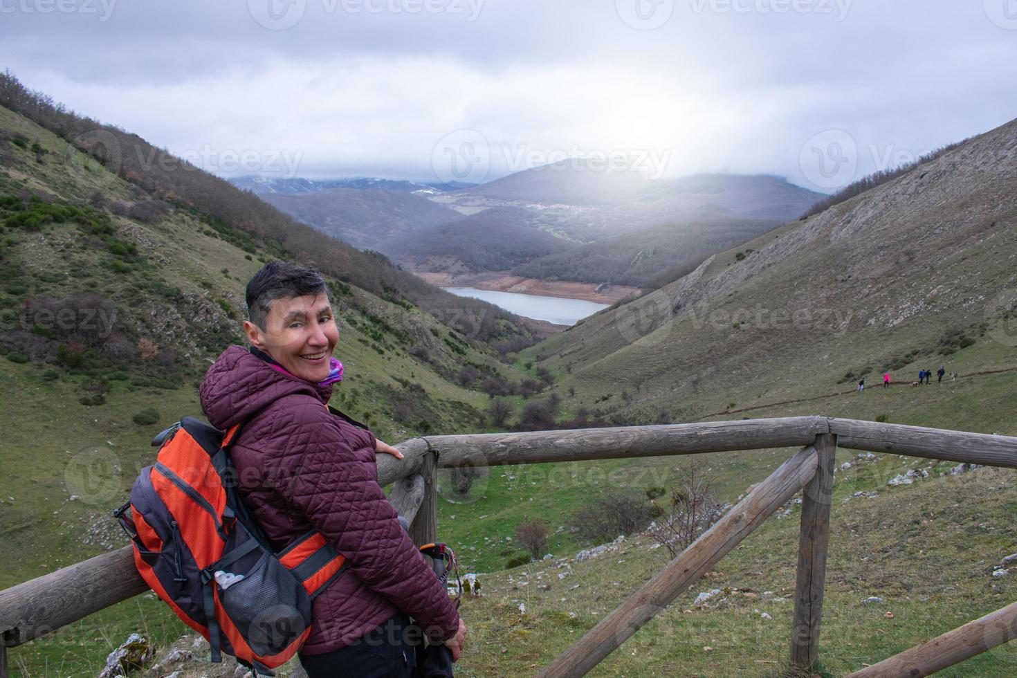 escursionista donna con zaino sorridente in un punto di vista di montagna foto