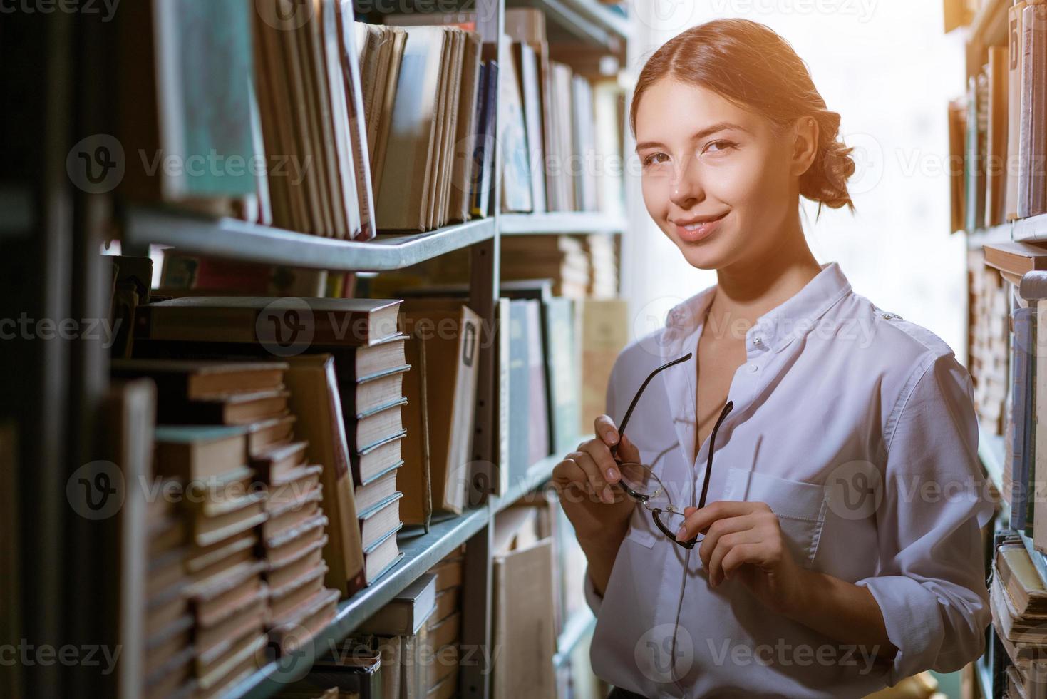 bella studentessa sta tra le file della biblioteca, foto