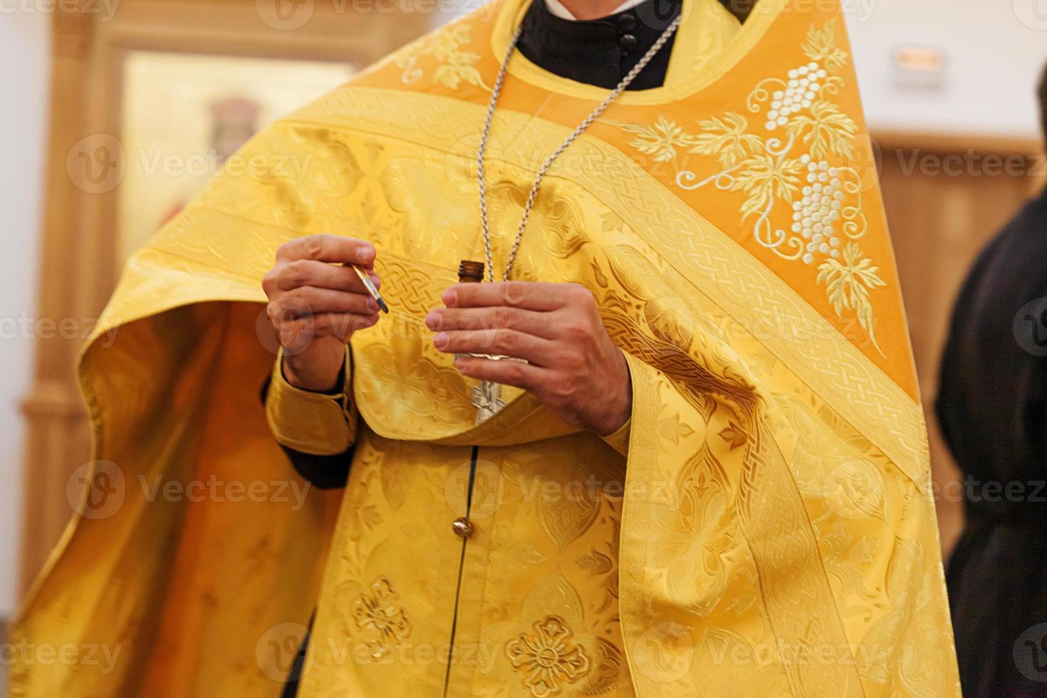 Chiesa ortodossa. cristianesimo. mani del sacerdote che tengono olio per l'unzione al battesimo sullo sfondo della chiesa ortodossa tradizionale. religione fede pregare simbolo. celebrazione del battesimo ortodosso. foto