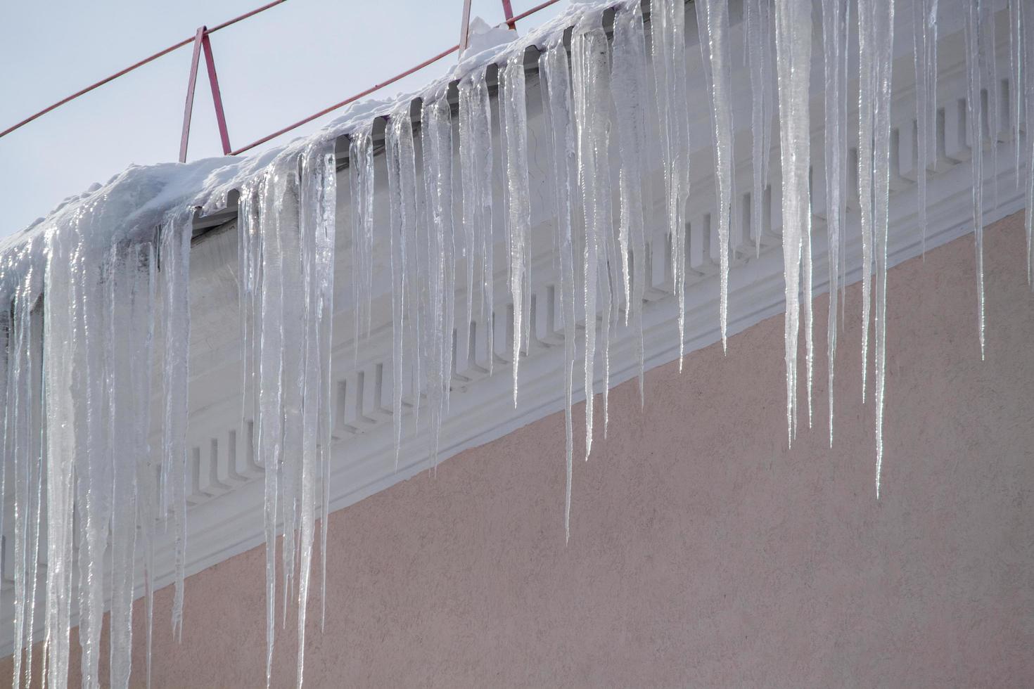 vista di lunghi ghiaccioli taglienti che pendono dal tetto della casa. foto