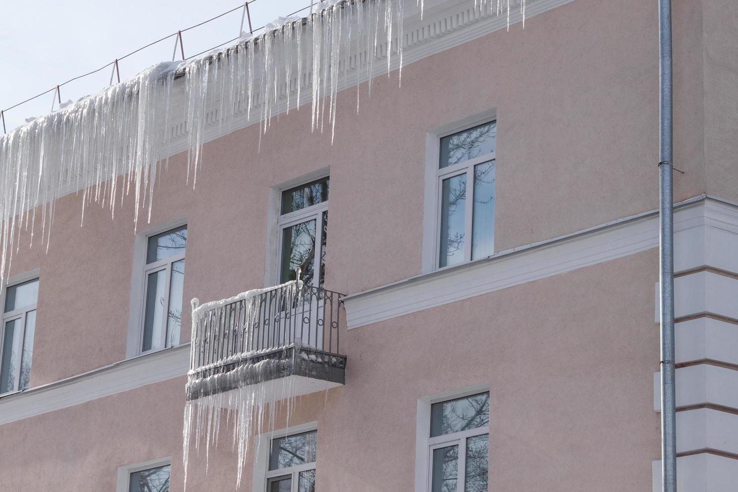 ghiaccioli taglienti pericolosi che pendono dal tetto e dal balcone. foto