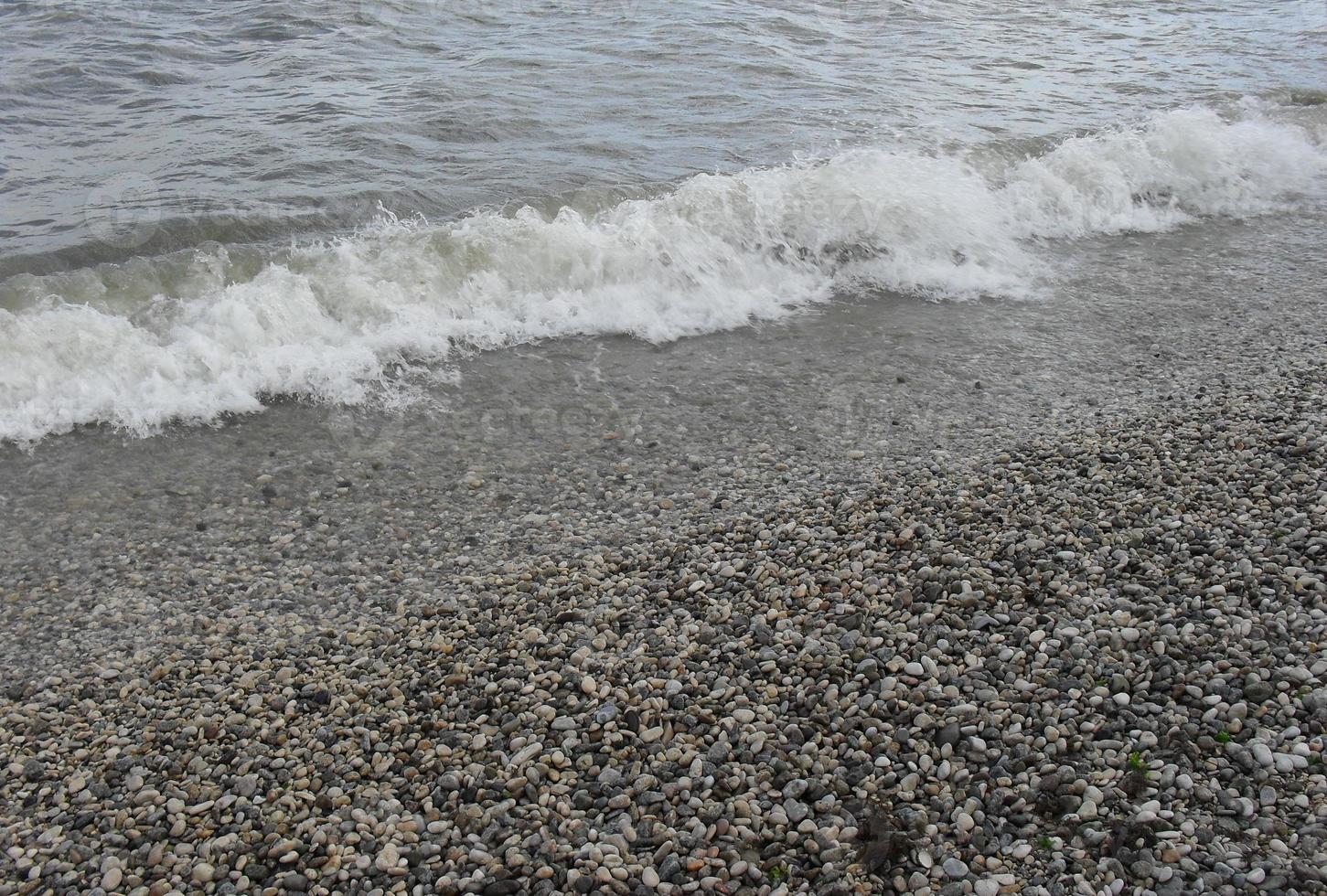 onda del mare con schiuma sulla riva con ciottoli. sfondo, bandiera, estate, viaggio foto