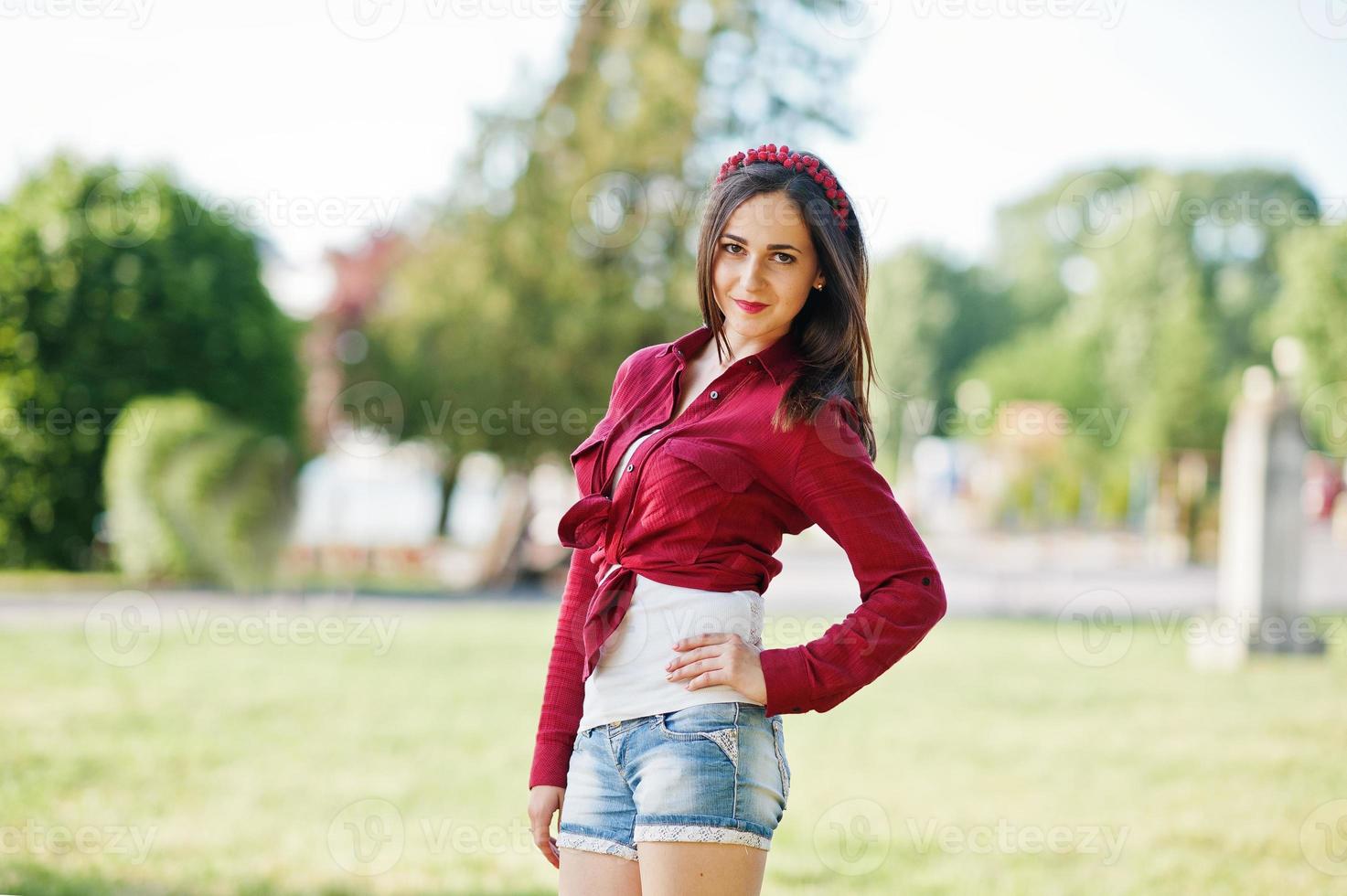 ritratto di ragazza di campagna in stile su pantaloncini di jeans corti e camicia a scacchi crosscountry foto