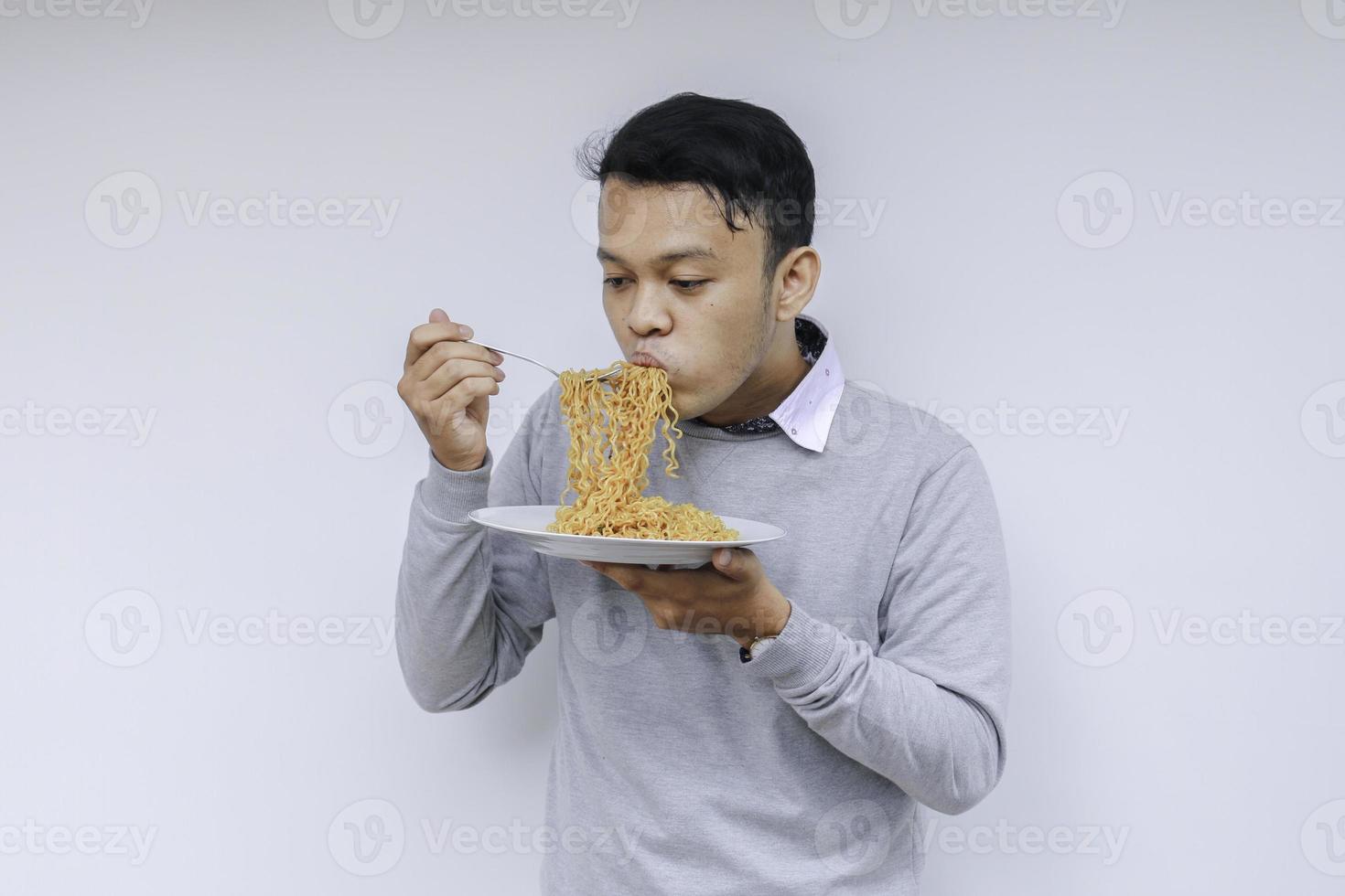 il giovane uomo asiatico si diverte con le tagliatelle. mangiare il concetto di pranzo. foto