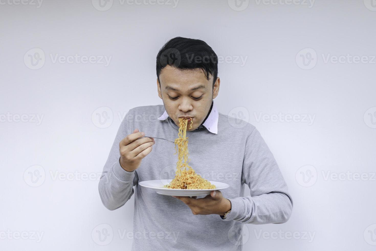 il giovane uomo asiatico si diverte con le tagliatelle. mangiare il concetto di pranzo. foto