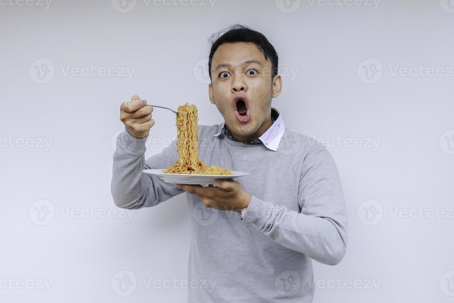 ritratto di shock e wow il giovane asiatico si diverte con i noodles. mangiare il concetto di pranzo. foto