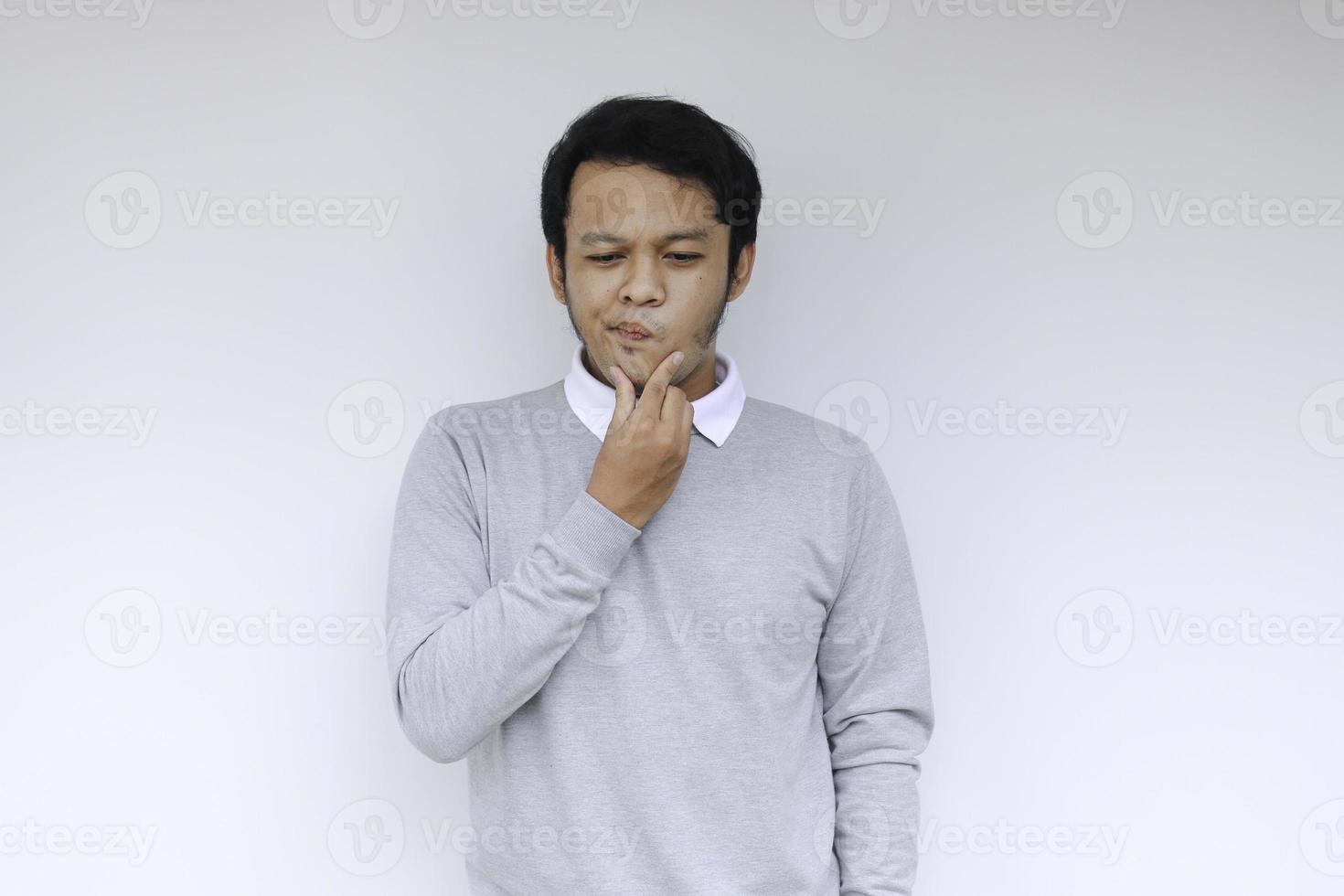 il giovane uomo asiatico indossa una camicia grigia con un gesto di idea di pensiero e sguardo foto