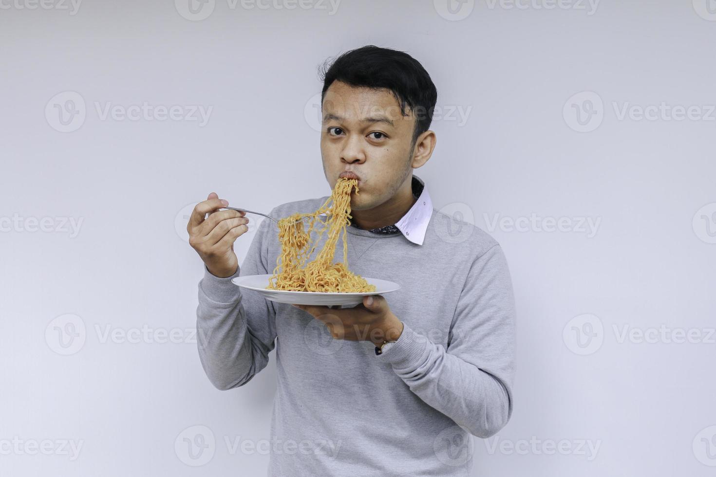 il giovane uomo asiatico si diverte con le tagliatelle. mangiare il concetto di pranzo. foto