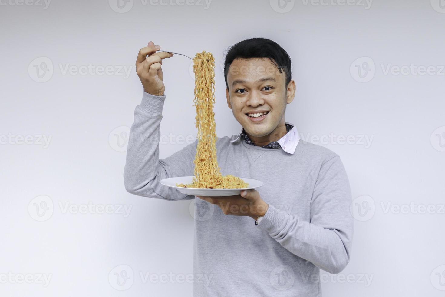 ritratto di felice giovane asiatico gode di noodles. mangiare il concetto di pranzo. foto