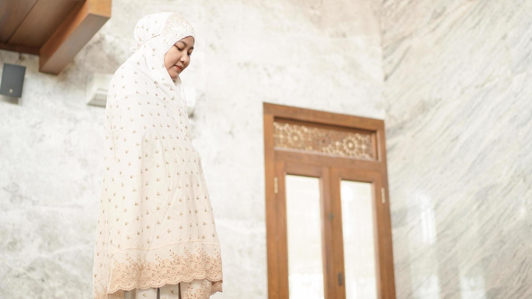 le donne musulmane asiatiche eseguono le preghiere obbligatorie nella moschea foto