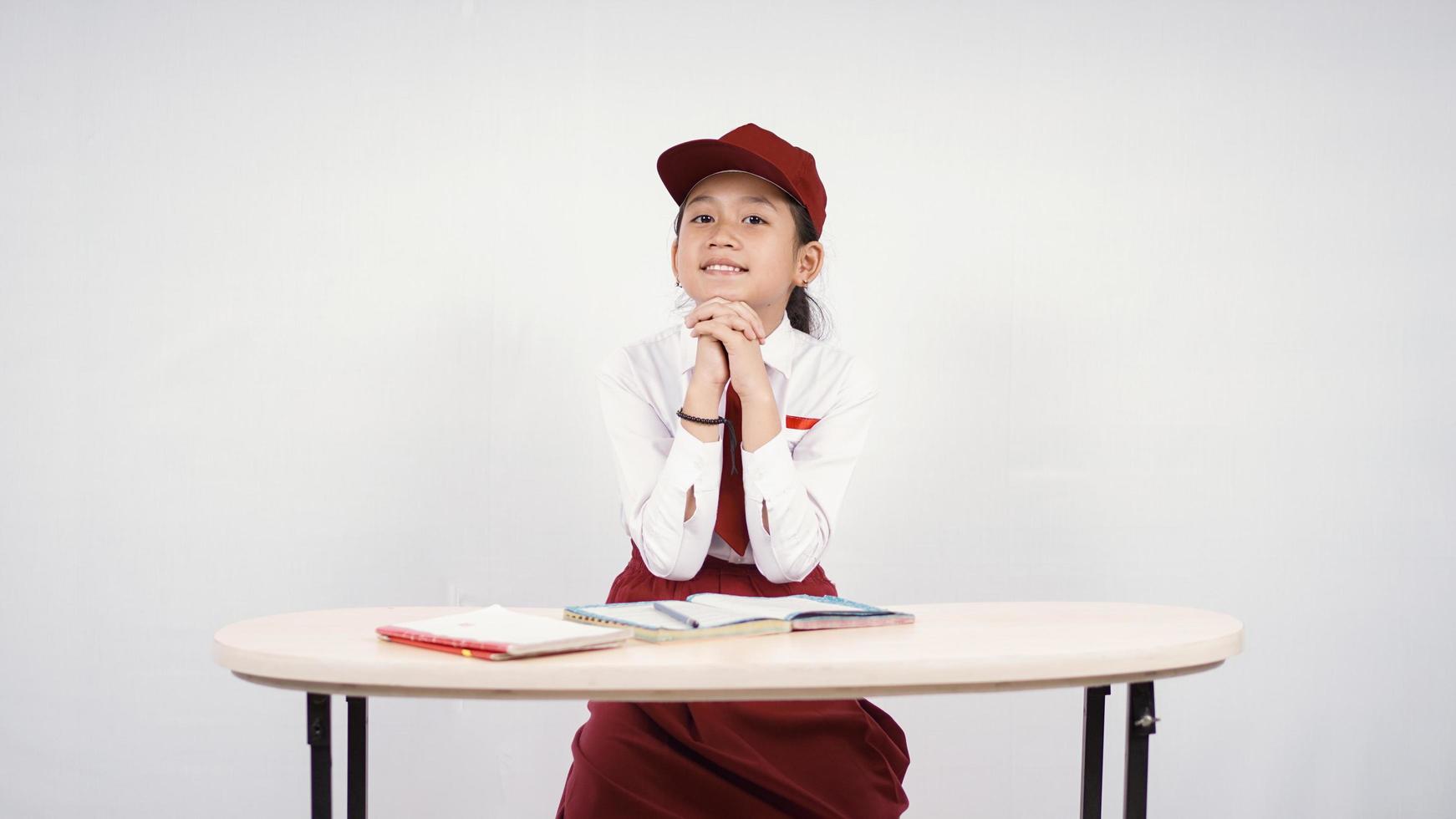 ragazza asiatica della scuola elementare che studia con passione isolata su fondo bianco foto