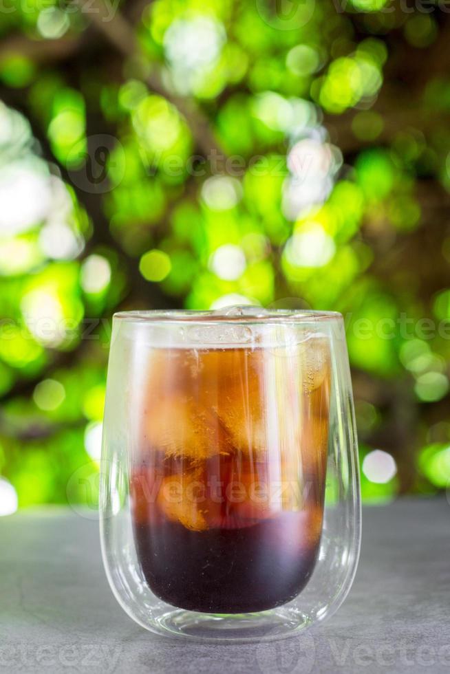 caffè freddo con succo d'arancia e ghiaccio su sfondo verde bokeh. foto