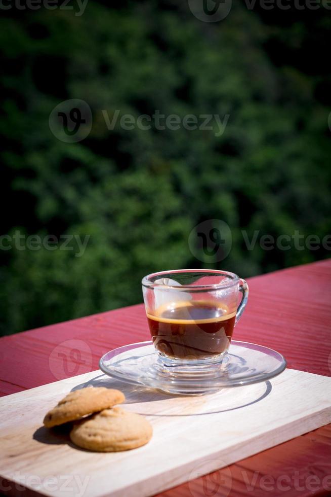 caffè espresso o nero servito con burro e biscotti alla vaniglia su tavola di legno con sfondo naturale verde. bevanda energetica al concetto di mattina. foto