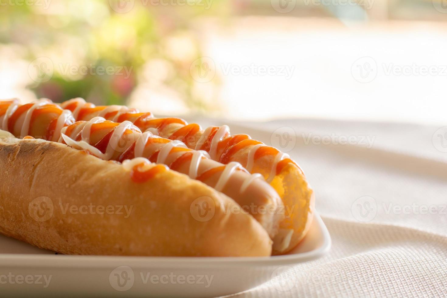 hot dog con panino e ketchup, maionese su piatto bianco. panino con salsiccia per pranzo. concetto di fast food. foto