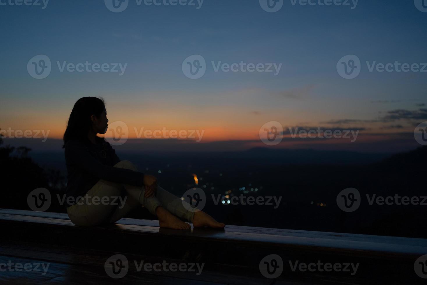 silhouette di donna seduta sulla terrazza e guardando il tramonto sulla montagna foto