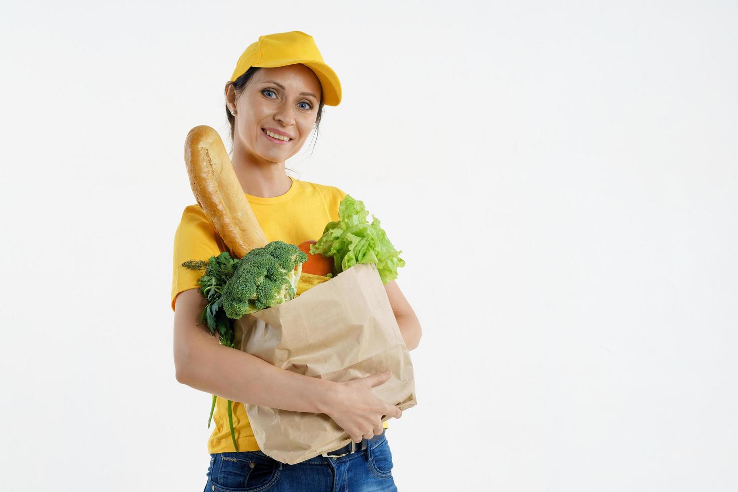 donna di consegna sorridente in posa gialla con il sacchetto della spesa, fondo bianco foto