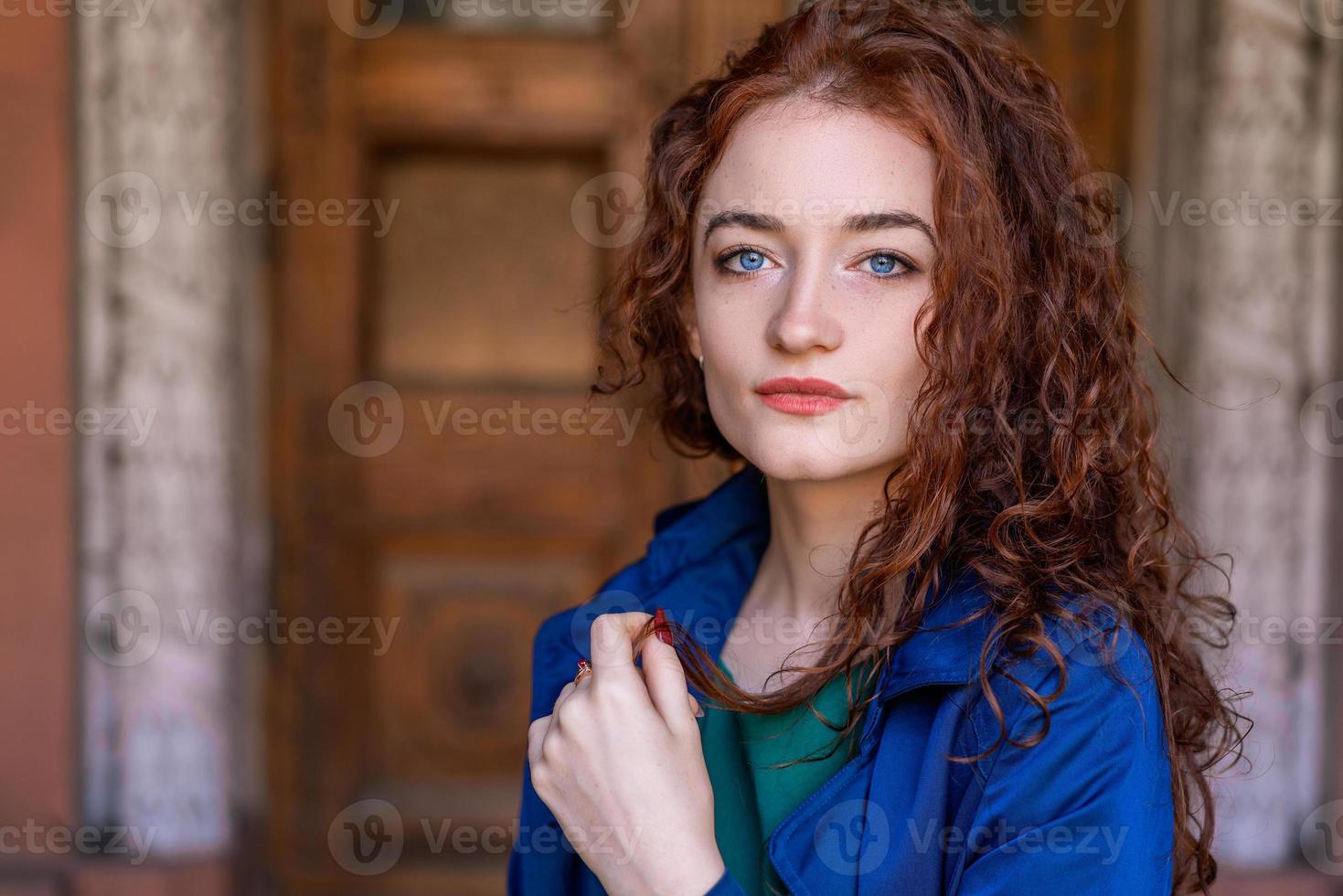 ritratto di bella donna con i capelli rossi in mantello blu in posa sulla fotocamera foto