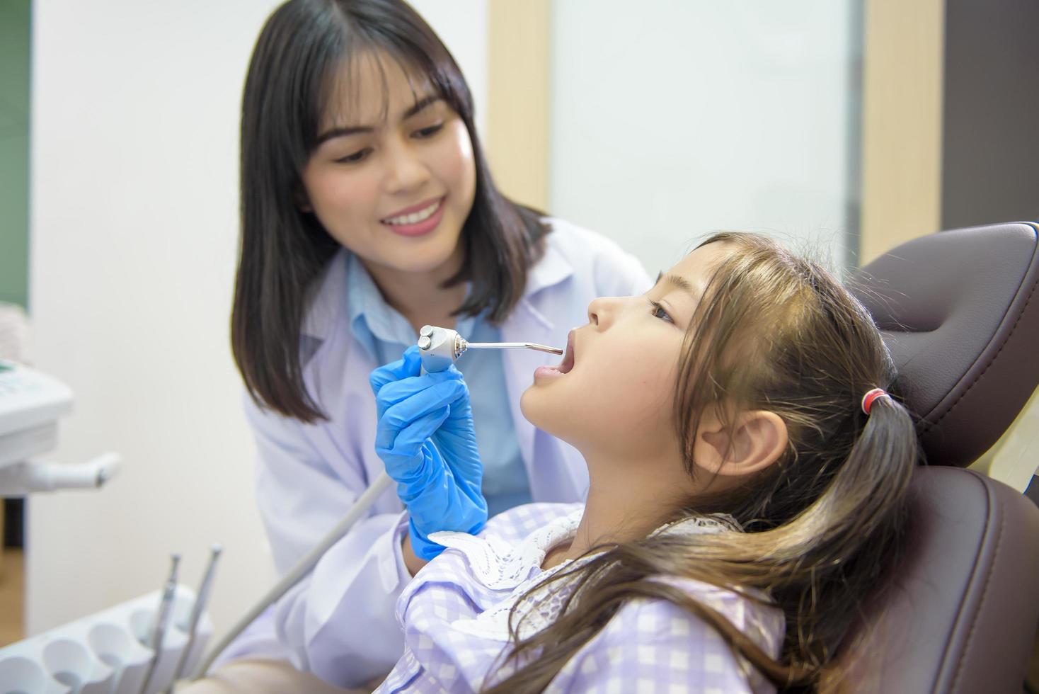 una piccola ragazza carina che ha i denti esaminati dal dentista in clinica dentale, controllo dei denti e concetto di denti sani foto