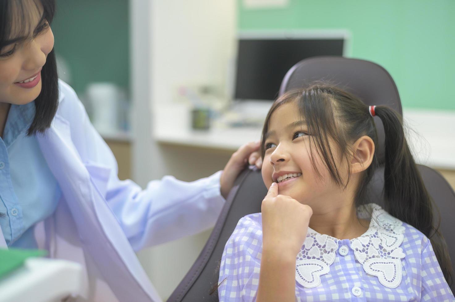 una piccola ragazza carina che ha i denti esaminati dal dentista in clinica dentale, controllo dei denti e concetto di denti sani foto