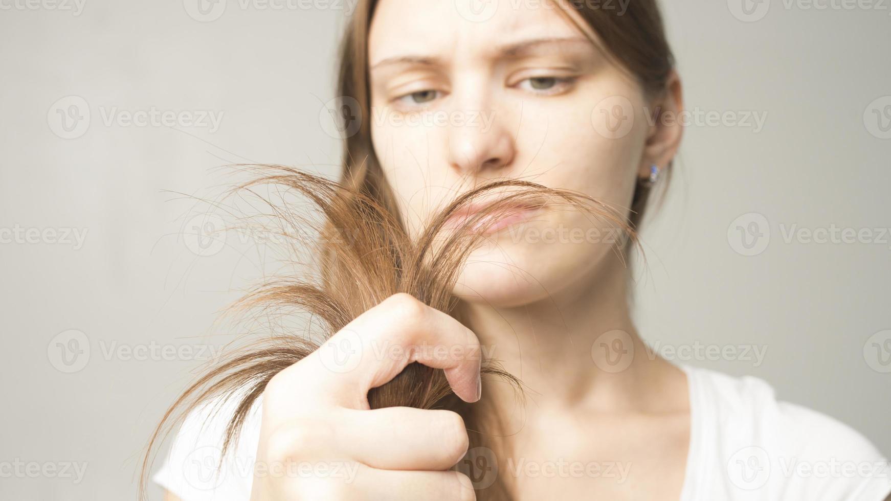 ragazza su sfondo grigio tiene un capello in mano foto