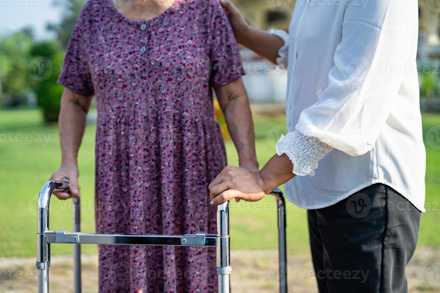 aiutare e curare la donna anziana o anziana asiatica anziana usa il camminatore con una buona salute mentre cammina al parco in una felice vacanza fresca. foto