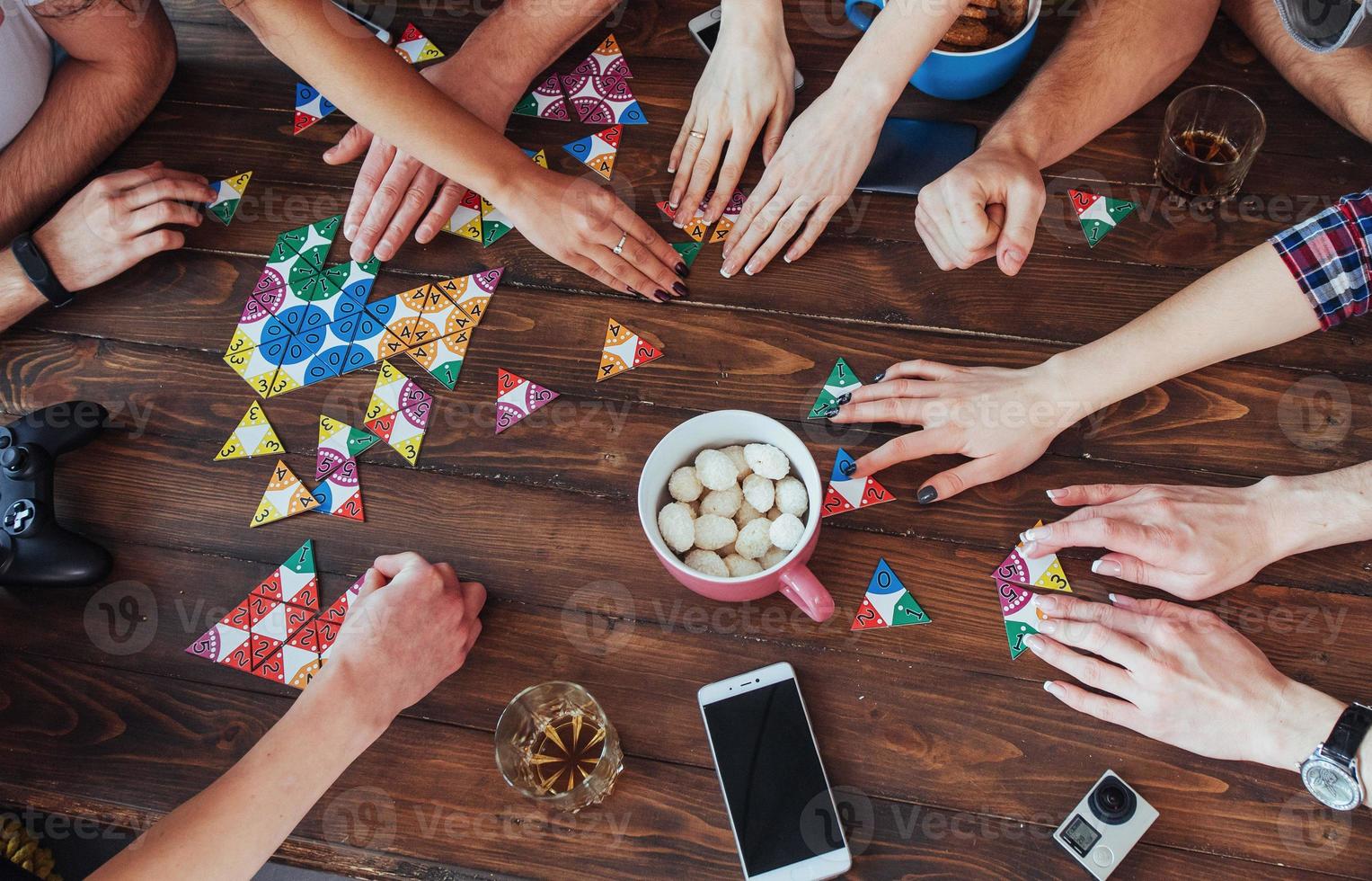 vista dall'alto foto creativa di amici seduti al tavolo di legno. divertirsi giocando a giochi da tavolo