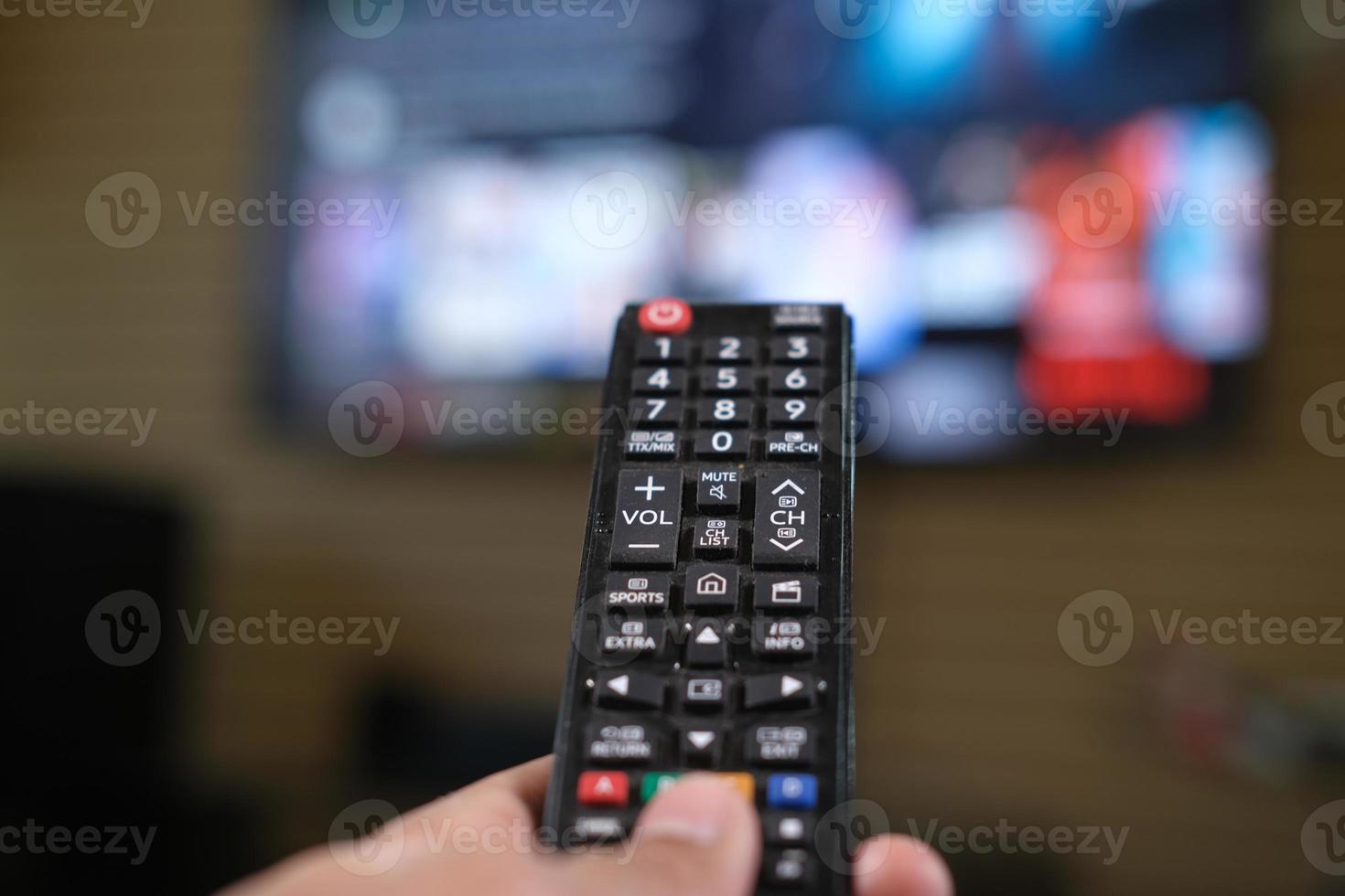 primo piano della mano dell'uomo che tiene il telecomando della tv. foto