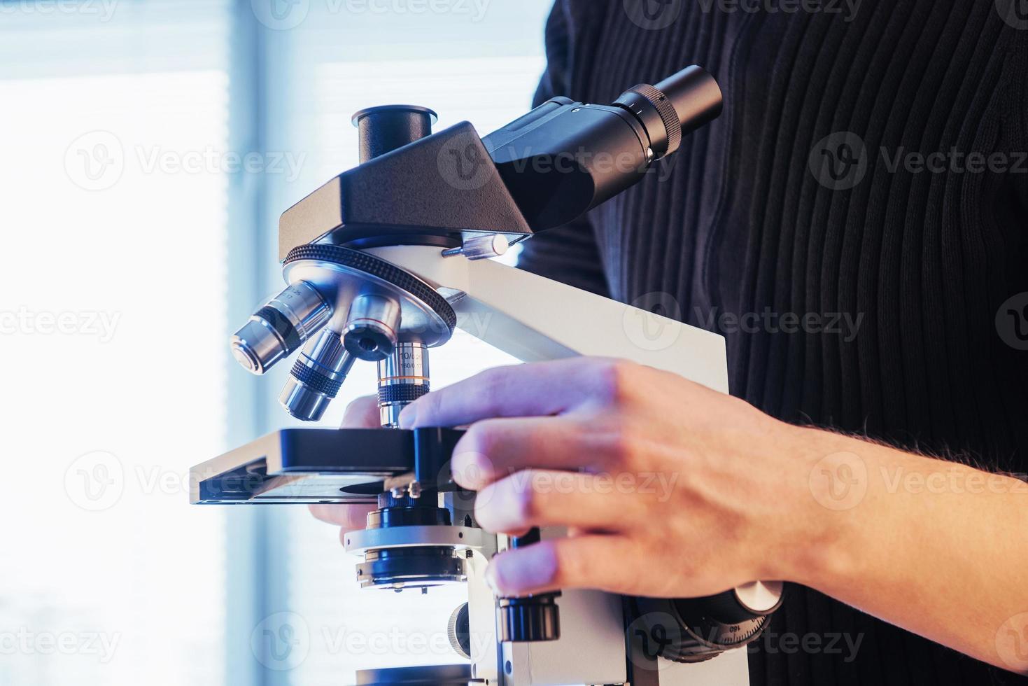 primo piano delle mani dello scienziato con il microscopio, esaminando i campioni. foto