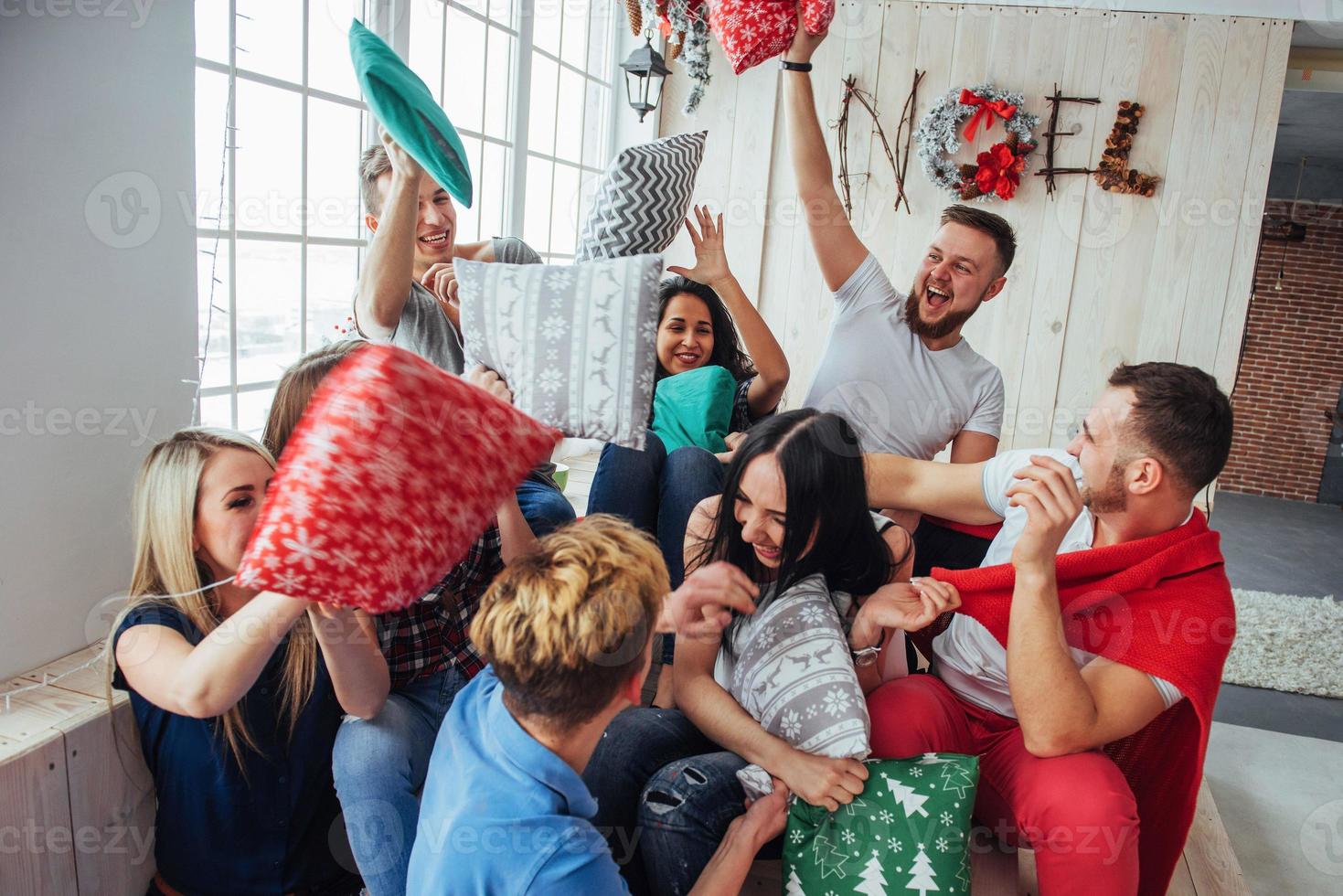 pazzi giovani migliori amici che combattono i cuscini a casa. gruppo di persone di razza mista. concetto di intrattenimento e stile di vita foto