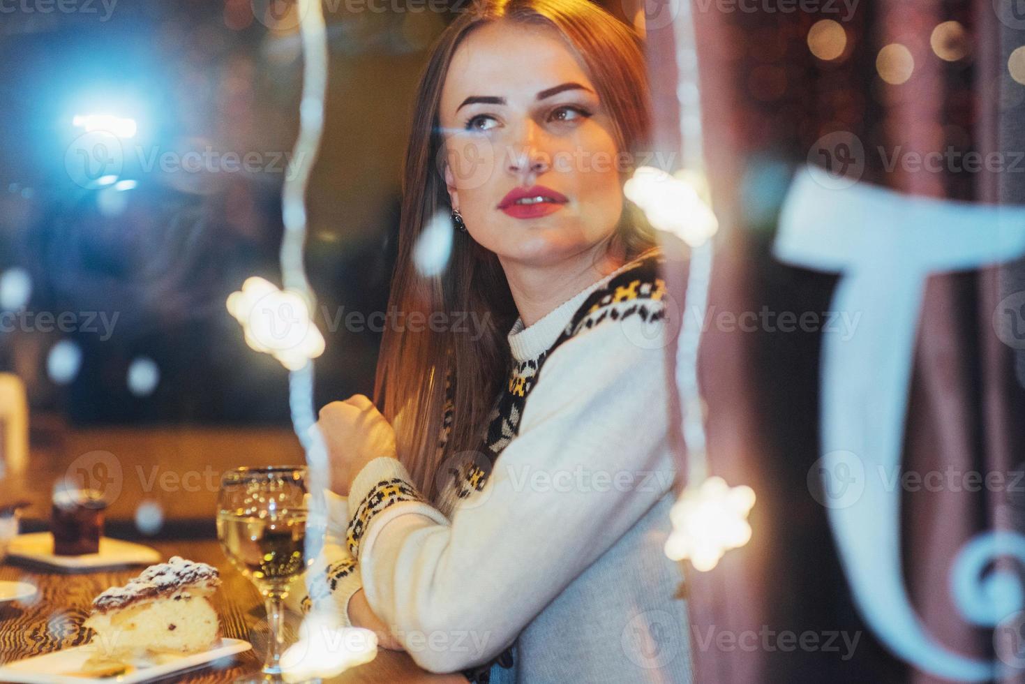 giovane bella donna seduta in un caffè, bere vino. natale, capodanno, san valentino, concetto di vacanze invernali foto