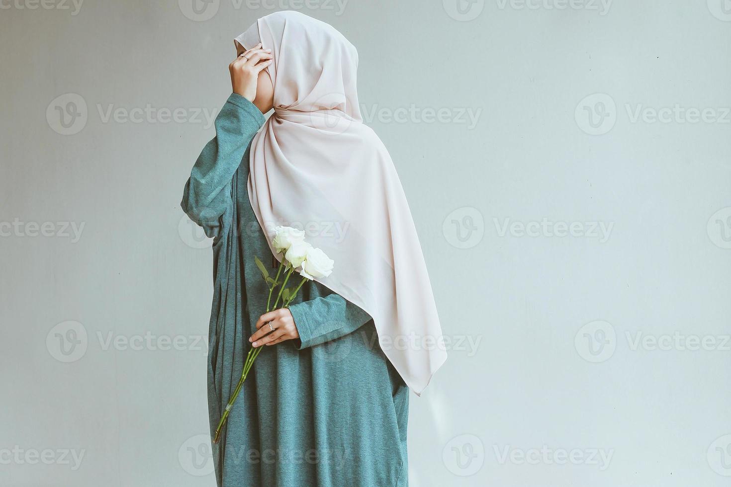 giovane donna musulmana in piedi e in posa mentre si copre il viso foto