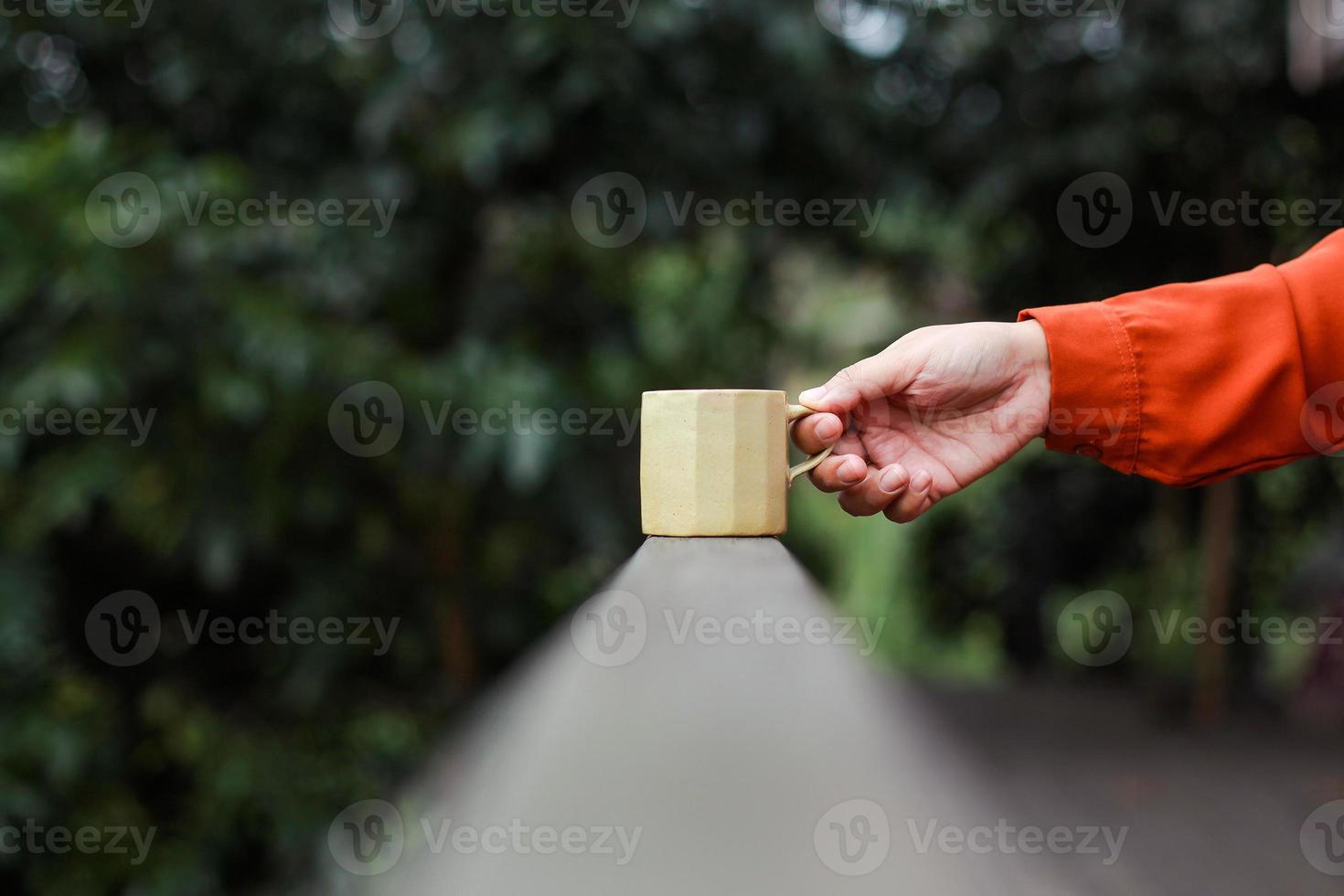 fuoco selettivo della mano che tiene il caffè con una bellissima natura sfondo sfocato foto