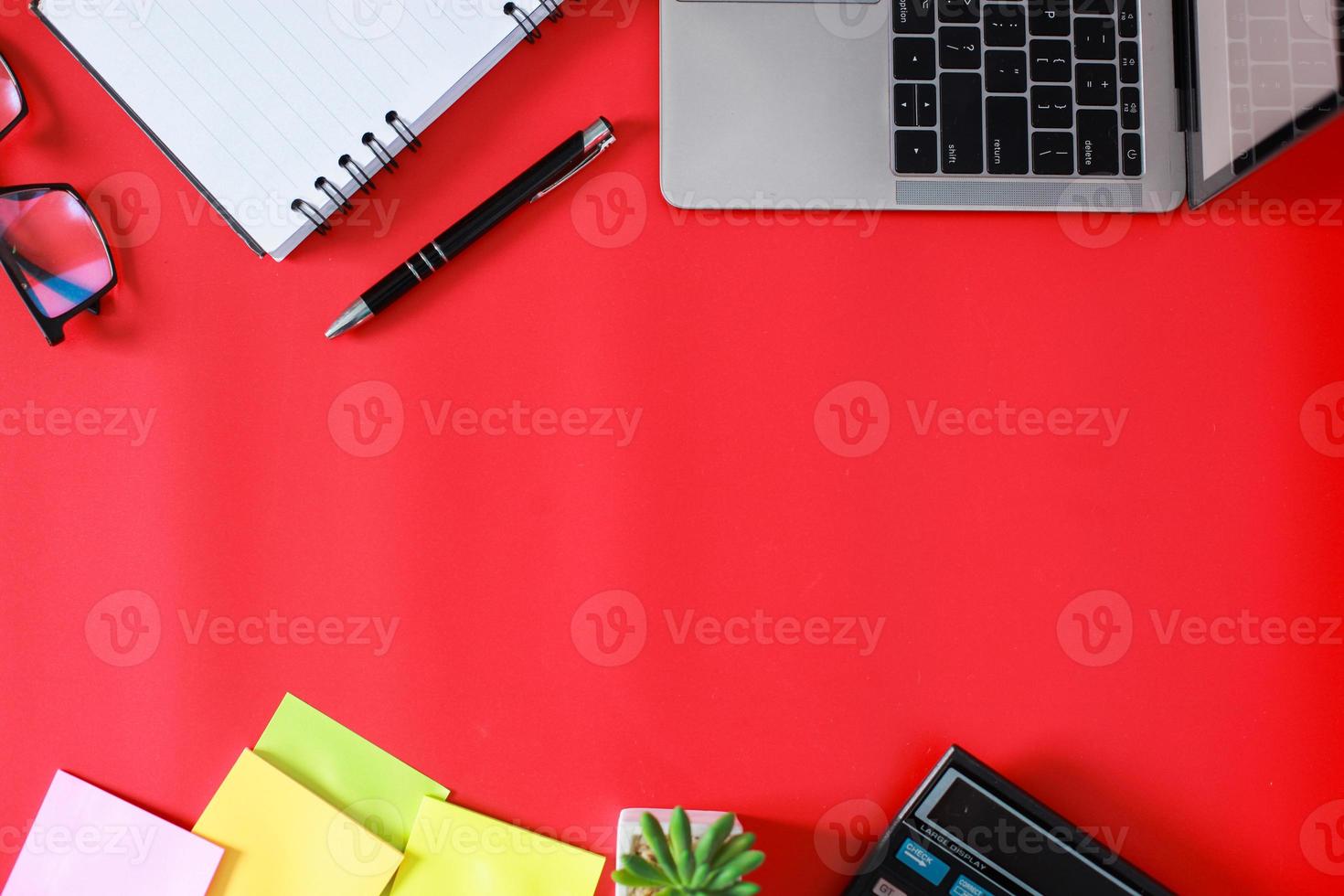 vista dall'alto piatta dell'elegante spazio di lavoro dell'home office con laptop, libro, succulente e accessori isolati su sfondo rosso, spazio libero o spazio per la copia foto