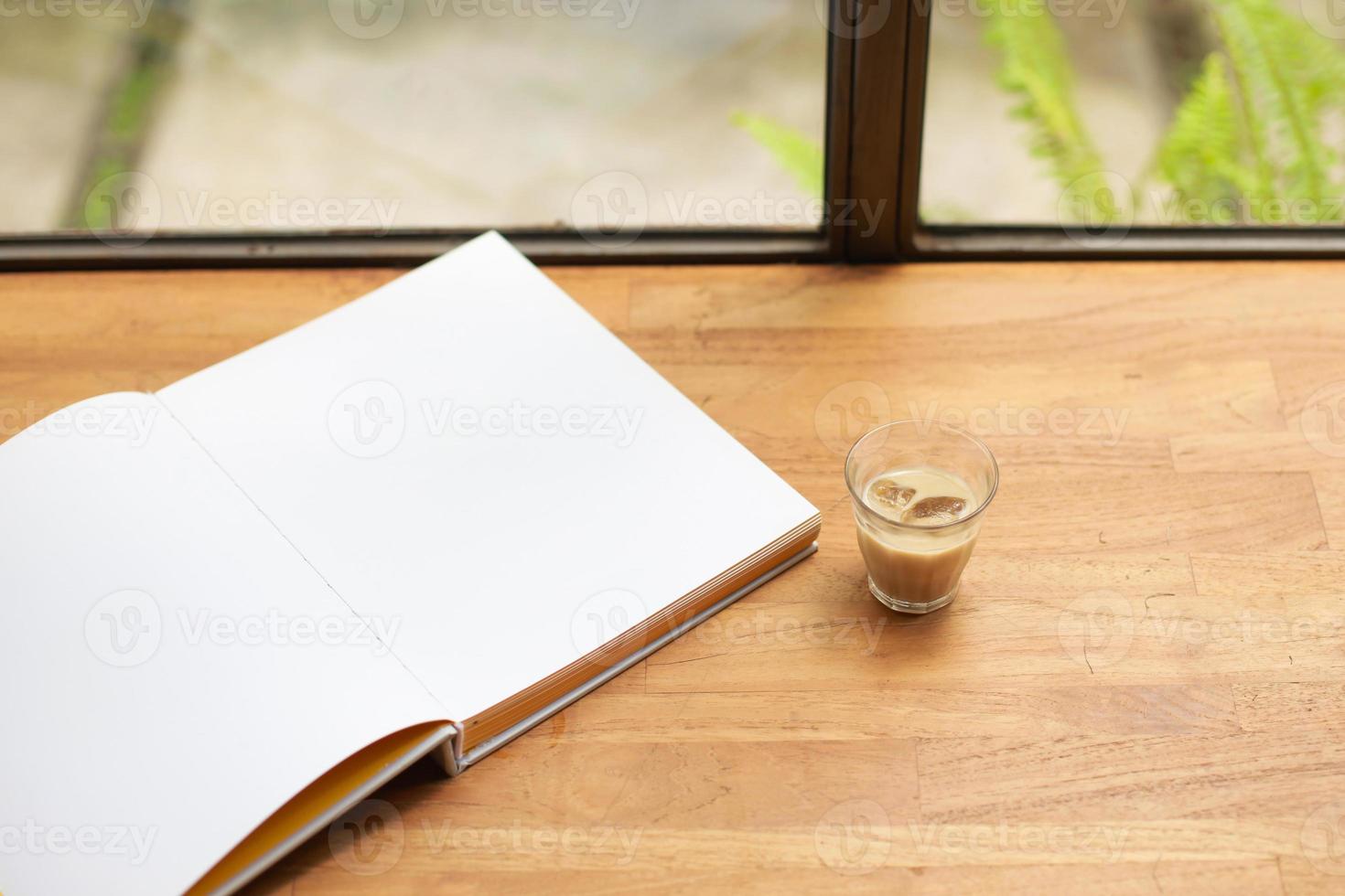 libro bianco vuoto aperto con caffè freddo sul tavolo di legno foto